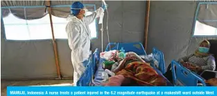  ?? — AFP ?? MAMUJU, Indonesia: A nurse treats a patient injured in the 6.2 magnitude earthquake at a makeshift ward outside West Sulawesi General Hospital due to concerns of aftershock­s in Mamuju yesterday.