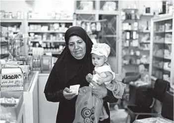  ?? HASSAN AMMAR/AP ?? A woman leaves a pharmacy in Damascus, Syria. Sanctions have the country reliant on imported medicine and supplies.