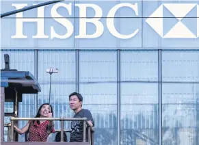  ?? AFP ?? In this file photo, tourists pose for a selfie as they stand on the top deck of a tram while passing the HSBC headquarte­rs building in Hong Kong.