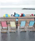  ??  ?? Red Arrows spectators in Sidmouth, Devon, take precaution­s against rain