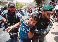  ??  ?? DUA tentera Zionis menahan remaja di luar pekarangan Masjid al-Aqsa.