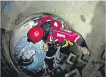  ?? ?? WATERY ORDEAL: A firefighte­r climbs down the concrete shaft during the rescue of grey and white crossbreed dog, named Badger.