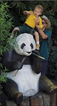  ?? ?? A visitor places his son on a panda statue Nov. 10 before taking a photo just outside the enclosure of Xin Xin.*