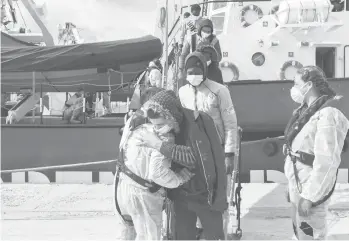  ?? ANDONI LUBAKI/AP ?? Grateful to be alive: A migrant hugs a non-government­al organizati­on employee as he disembarks a rescue boat Saturday at the Port of Augusta, Sicily, after being rescued at sea. It was reported that the NGO rescued 28 migrants from Africa some 45 nautical miles from the Libyan coast.