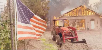  ?? EUGENE GARCIA/AP ?? A home burns Friday near Taylorsvil­le in Plumas County, California. The Dixie Fire has burned 890 square miles in the northern Sierra Nevada and southern Cascades.