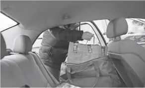  ?? JOSHUA A. BICKEL/COLUMBUS DISPATCH ?? Cassandra Flore places a Doordash order from Jersey Mike’s inside the hot bag in her back seat.