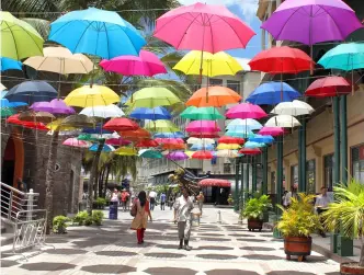  ?? PHOTOS: © STEEVE DUBOIS | DREAMSTIME.COM, © NICO KELDER | DREAMSTIME.COM, © BYVALET | DREAMSTIME.COM ?? Brilliant Hues:
Colorful umbrellas overhead at Le Caudan Waterfront (top), breathtaki­ng views from Le Pouce of the surroundin­g landscape (middle), and Blue Penny Museum in Port Louis (bottom)