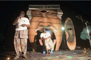  ??  ?? (Left) A Togolese profession­al storytelle­r speaks to the public gathered in Sainte Cecile Square in Cotonou during a night of tales. Each year in August, more than thirty municipali­ties, small villages or large cities host the night of tales. • (Right) Profession­al storytelle­r Agbanglano­n Cosme Patrice talks to the public gathered in Sainte Cecile Square. — AFP photos