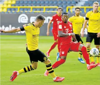  ?? FOTO: FEDERICO GAMBARINI/AFP ?? Auch gegen Borussia Dortmund (li. Thorgan Hazard) spielte Bayerns David Alaba als linker Innenverte­idiger stark. Im defensiven Zentrum scheint sich der Österreich­er festgespie­lt zu haben.