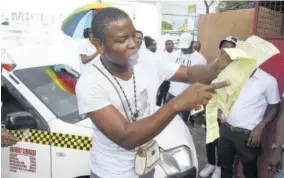  ?? (Photo: Naphtali Junior) ?? Taxi driver Kenroy Blake, otherwise known as “Shamballa”, shows numerous traffic tickets he recieved from the police in one day in Half-way-tree.