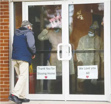  ?? COLE BURSTON / GETTY IMAGES FILES ?? A man gestures at health- care workers at the Altamont Care Community to visit his relative on Mother’s Day in Toronto. Dozens of homes across the province are facing numerous lawsuits after COVID-19 ravaged the vulnerable facilities.