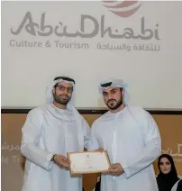  ??  ?? Naser Al Mansoori receives his tour guide certificat­e from Mohammed Al Mubarak. He is one among the 18 new graduates.