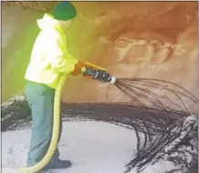  ??  ?? A West Goshen Township employee sprays beet juice onto a pile of road salt.