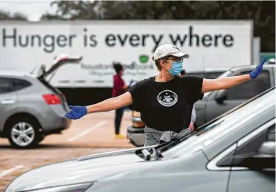  ?? Photos by Marie D. De Jesús / Staff photograph­er ?? Houston Food Bank volunteer Cecilie Tindlund directs traffic during a meal distributi­on event at NRG Park on Sunday.