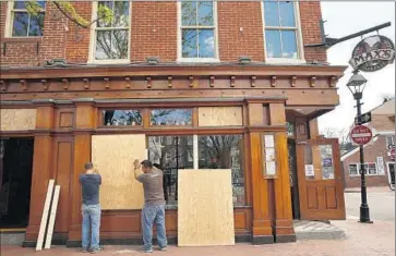  ?? Carolyn Cole
Los Angeles Times ?? WORKERS BOARD UP the windows at Max’s Taphouse in Baltimore’s Fells Point neighborho­od. Many bars in the area took similar measures, but they remained open for business during the daytime.