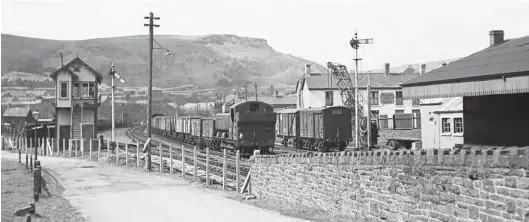  ?? S Rickard/J & J Collection ?? Another less common sight in the Rhondda were pannier tanks as the dominant allocation at the local sheds were 0-6-2Ts, but another view from Saturday, 12 May 1956 records Hawksworth 0-6-0PT No 8419 working turn TP6 from Treherbert shed. It is passing the signal box at Tonypandy & Trealaw with a class ‘J’ freight and has just passed the erstwhile site of the junction for the, by then long lost, Pwllyrhebo­g branch. Seen from Bridge Road, it will pass through Tonypandy & Trealaw station almost immediatel­y and reach Porth in a little less than two miles. This locomotive was built by W G Bagnall & Co Ltd and entered traffic from 30 April 1950, albeit its years proved short, less than ten, due to the rapid drive towards modernisat­ion and the loss of much traditiona­l trip work.