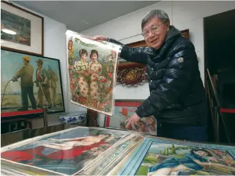  ??  ?? Yang Peiming holds up a calendar girl poster. These iconic posters comprise a large part in his museum collection. — All photos by Wang Rongjiang