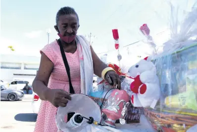  ?? PHOTOS BY KENYON HEMANS/PHOTOGRAPH­ER ?? Kay Williams, a vendor in the Constant Spring Arcade, takes to the roadside to catch Valentine’s sales amid a slump in business.