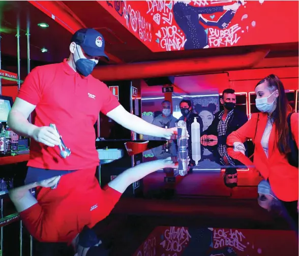  ??  ?? Un camarero sirve una bebida a una joven en el interior de una discoteca en Madrid
