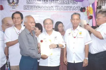  ??  ?? Uggah (centre) presents a grant to a longhouse representa­tive. Also seen are (from right) Tiong, Penguang and Anyi.