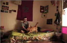  ?? NARIMAN EL-MOFTY — THE ASSOCIATED PRESS ?? In this Thursday photo, Yassin Mohammed sits with a cat in an apartment he shares, in Cairo, Egypt.