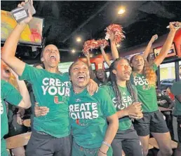  ?? PATRICK FARRELL/MIAMI HERALD ?? University of Miami basketball players Adrienne Motley and Jessica Thomas, center, celebrate with their teammates as they received the good news.