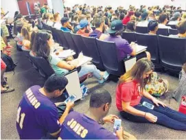  ?? GABRIELLE RUSSON/STAFF ?? There is not enough room for all the University of Central Florida students in a business class. Students sit on the floor or lean against the wall in the back of the lecture hall.