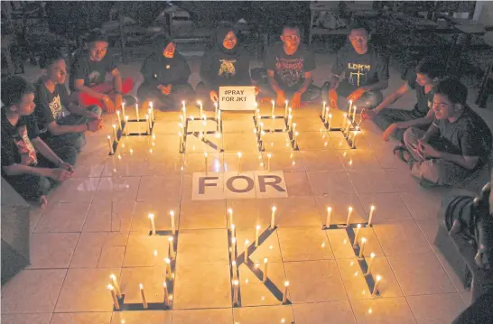  ?? AP ?? Students in Surabaya, East Java, light candles for those affected by the deadly attacks in Jakarta. Indonesian­s have been shaken by the violence in the busy central district of the capital.