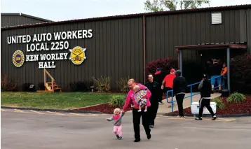  ?? Associated Press ?? ■ United Auto Worker Lindsey Higgins exits the the UAW Local 2250 Ken Worley Hall with her two children on Thursday after voting on the offer made to union workers by General Motors in Wentzville, Mo. General Motors workers voted 57.2% in favor of a new contract with the company, bringing an immediate end to a contentiou­s 40-day strike that paralyzed GM’s U.S. factories.