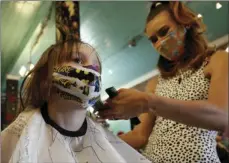  ?? AP PHOTO/RICH PEDRONCELL­I ?? In this May 4 file photo, Robin Sotomayor, 5, wears a Supergirl face mask as she gets her hair done by Haylee Cummins at Rockabetty’s Hair Parlor, in Yuba City, Calif.