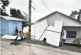  ?? DANIEL PARRA AP ?? Residents of San Andres island, Colombia, pick up pieces of a damaged roof in the aftermath of Hurricane Julia on Sunday. Julia hit Nicaragua’s central Caribbean coast after lashing San Andres island, and a weakened storm was expected to emerge over the Pacific.