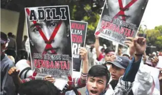  ??  ?? JAKARTA: A Muslim man shouts slogans as he holds a defaced poster of Myanmar’s Foreign Minister Aung San Suu Kyi during a rally against the persecutio­n of Rohingya Muslims outside the Embassy of Myanmar yesterday. — AP