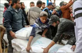  ?? Samar Abu Elouf/The New York Times ?? Flour is distribute­d by the United Nations Relief and Works Agency, or UNRWA, on Nov. 22 at its headquarte­rs in Khan Younis, in the southern Gaza Strip.