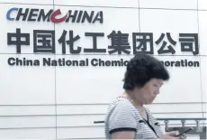  ?? — Reuters ?? A woman walks past the office of ChemChina in Beijing.