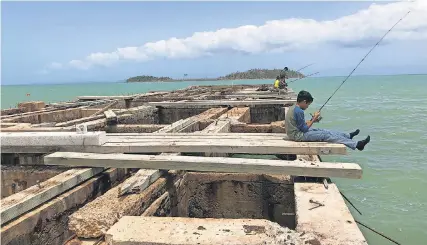  ?? RICK JERVIS/USA TODAY ?? Children fish from the remnants of the hurricane-ravaged fishing pier in Punta Santiago, Puerto Rico, which was once a hub of activity.