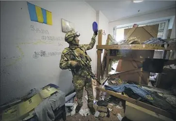  ?? Alexander Zemlianich­enko Associated Press ?? A RUSSIAN soldier gets a look at the base of Ukraine’s Azov regiment near the port city of Mariupol. Members of the regiment put up a spirited defense while holed up at the Azovstal steelworks besieged by Russia.