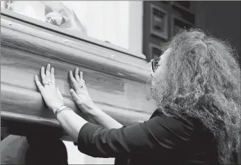  ?? ANGELO CARCONI/ANSA VIA AP ?? Carabinier­i officer Mario Cerciello Rega’s wife, Rosa Maria, touches the coffin of her husband as it arrives to be laid in state on Sunday in Rome. In a statement Saturday, Carabinier­i officers investigat­ing the death of Cerciello Rega, 35, said two young American tourists have been detained for the alleged murder.