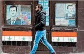  ?? LOUAI BESHARA/GETTY-AFP ?? A Syrian walks past posters of President Bashar Assad, who says peace talks depend on rebels’ participat­ion.