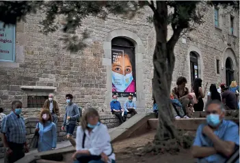  ??  ?? People wearing masks to protect against the spread of Coronaviru­s sit in front of the cathedral in Barcelona, Spain, on Saturday.