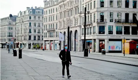  ?? — AFP ?? A pedestrian wearing a mask as a precaution­ary measure against Covid-19, walks past closed-down shops on an empty Regent Street in London on Thursday, as life in Britain continues during the nationwide lockdown to combat the pandemic.