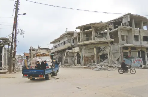  ?? MUHAMMAD HAJ KADOUR / AFP via Gett y Imag es ?? Syrians return to their homes on Friday in the town of Binnish, in the northweste­rn Idlib province near the Turkish border, following a Russia-turkey ceasefire deal. The truce is considered to be a fragile one.