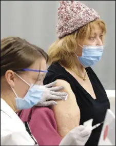  ?? Barbara J. Perenic/Columbus Dispatch ?? Dr. Rachel Ziemba, PharmD, holds gauze against the arm of Susan Paolucci, 84, a retired professor of English, after dispensing the COVID-19 vaccine on Tuesday, the first day that vaccine was available to the public, at the Jerome Schottenst­ein Center in Columbus on Jan. 19.