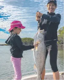  ??  ?? Sally Atkins heaves her black jewfish while daughter Lani, 8, admires the catch.