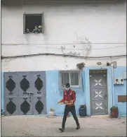  ??  ?? A man carries a tray of tea to Elmihnida and other volunteers while they clean a street.