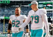  ?? ELSA / GETTY IMAGES ?? Ted Larsen (62) and offensive tackle Sam Young walk off the field after the Dolphins’ 20-12 win over the Jets on Sunday at MetLife Stadium.