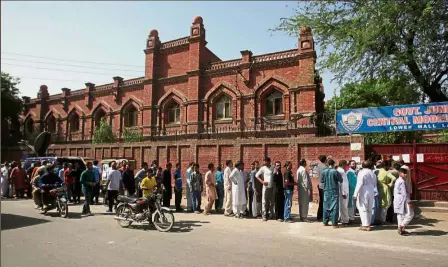  ??  ?? Waiting patiently: Voters lining up outside a polling station in Lahore. — Reuters