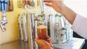  ?? SARAH ESPEDIDO/ORLANDO SENTINEL ?? A bartender pours a free 7-ounce beer The Patio by Mama’s Pretzels in May at SeaWorld Orlando.