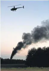  ?? ELIJAH BAYLIS, THE ( JACKSON, MISS.) CLARION- LEDGER ?? A helicopter flies over the smoking crash site of amilitary plane near Moorehead Road in Itta Bena, Miss., onMonday.