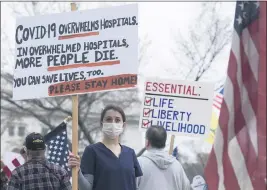  ?? MARK HOFFMAN — MILWAUKEE JOURNAL-SENTINEL ?? On April 24, a nurse demonstrat­ing in favor of business closures is surrounded by demonstrat­ors against Gov. Tony Evers’ restrictio­ns on daily life due to the coronaviru­s pandemic at the Capitol in Madison, Wis.