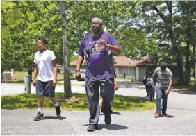  ?? STAFF PHOTO BY ERIN O. SMITH ?? Herbert “Book” McCray, 63, walks a group of boys to his car to help him sort through shirts at Booker T. Washington State Park. McCray has mentored youth as an educator, retired principal and coach for nearly three decades.